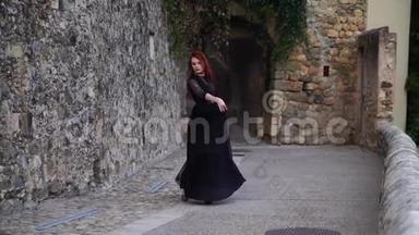 穿着黑色晚礼服、在中世纪城市的街道上跳舞的迷人女人听到红色的声音。